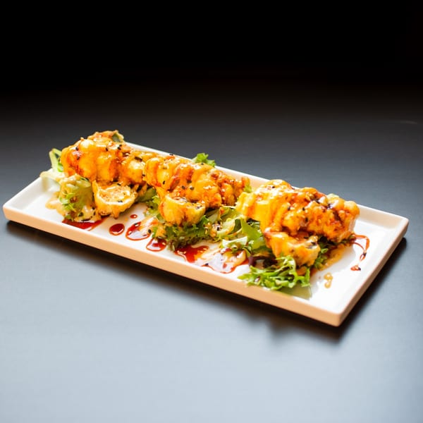 Three pieces of Yellowfinn Grill & Sushi Bar's sushi rolls, drizzled with sauce and sesame seeds.