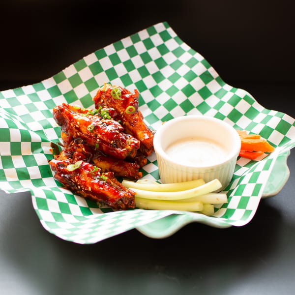 Yellowfinn Grill & Sushi Bar's spicy chicken wings with ranch, celery, and carrots on checkered paper.