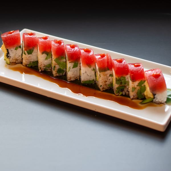 Yellowfinn Grill & Sushi Bar's tuna sushi roll with red sauce drizzle on a white rectangular plate.
